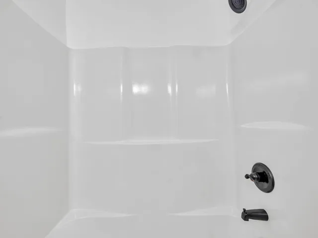 an empty room with wooden floor ceiling fan and window