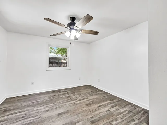 a view of an empty room with window and wooden floor