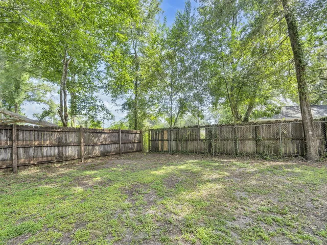 a house that is sitting in the grass with large trees