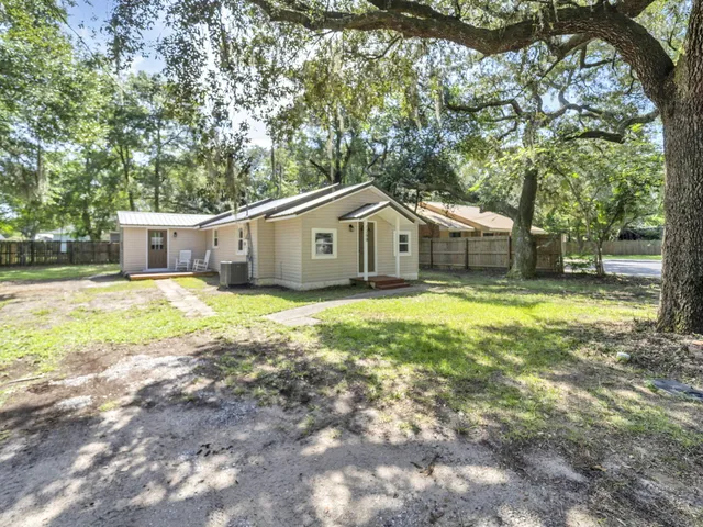 a view of a yard in front of a house with large trees