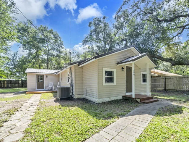a view of a white house with a big yard and large trees