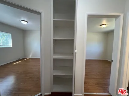 a view of an empty room with wooden floor and closet