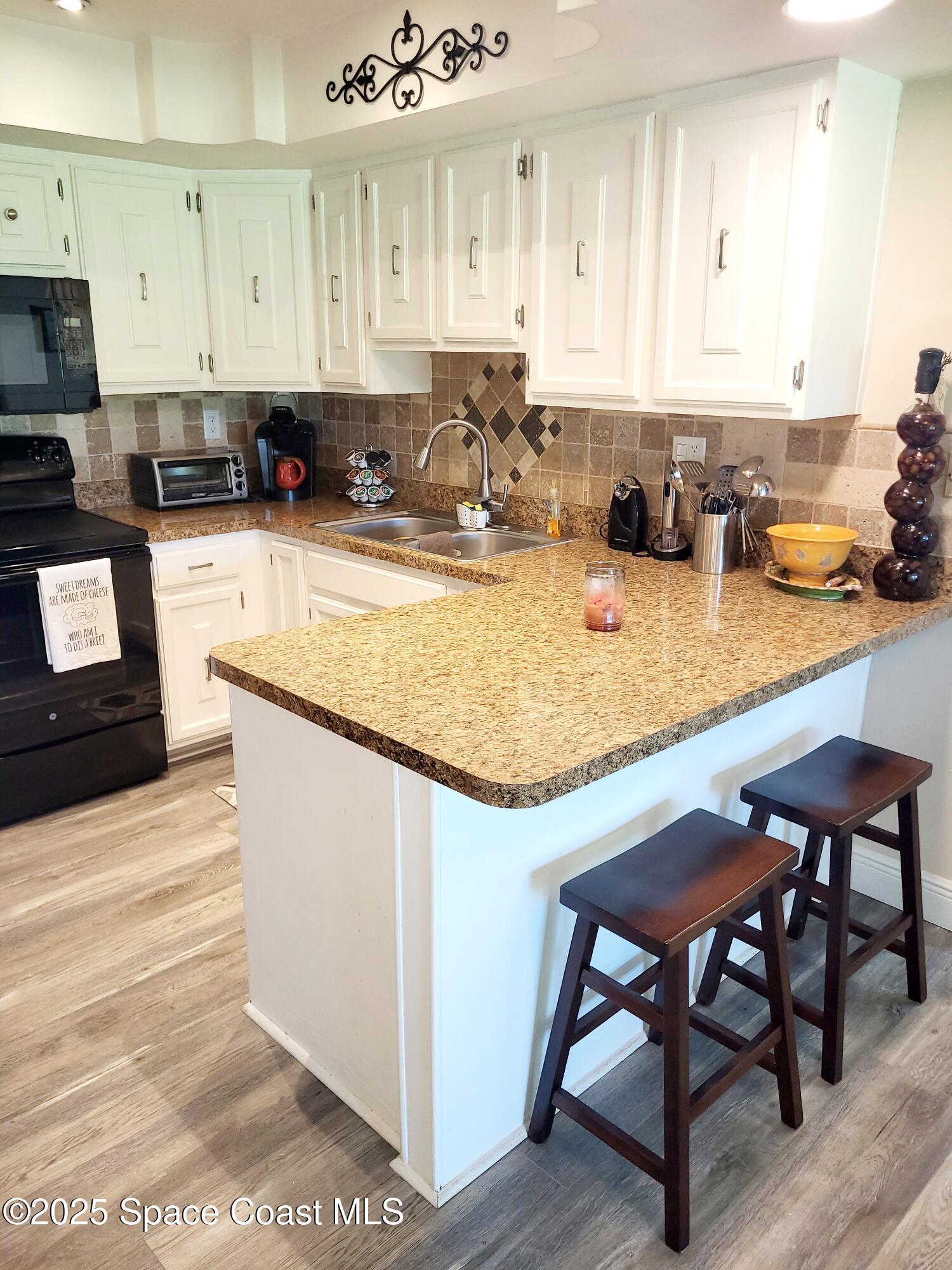 145 Augusta Way Melbourne, FL 32940 - Photo 11 of 28 a kitchen with stainless steel appliances granite countertop a stove top oven a sink a counter space and cabinets