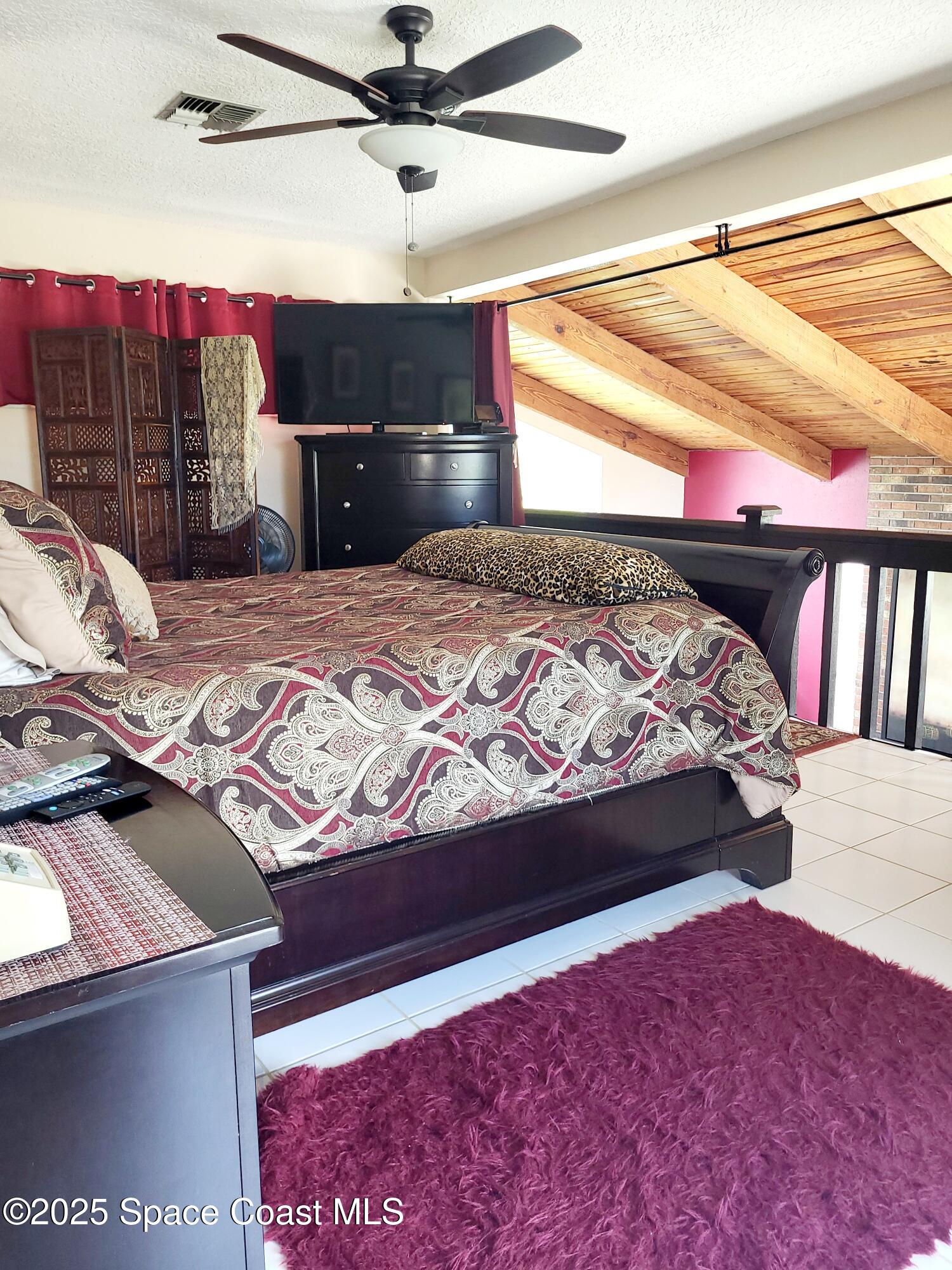 145 Augusta Way Melbourne, FL 32940 - Photo 20 of 28 a bedroom with a bed and a flat tv screen on dresser