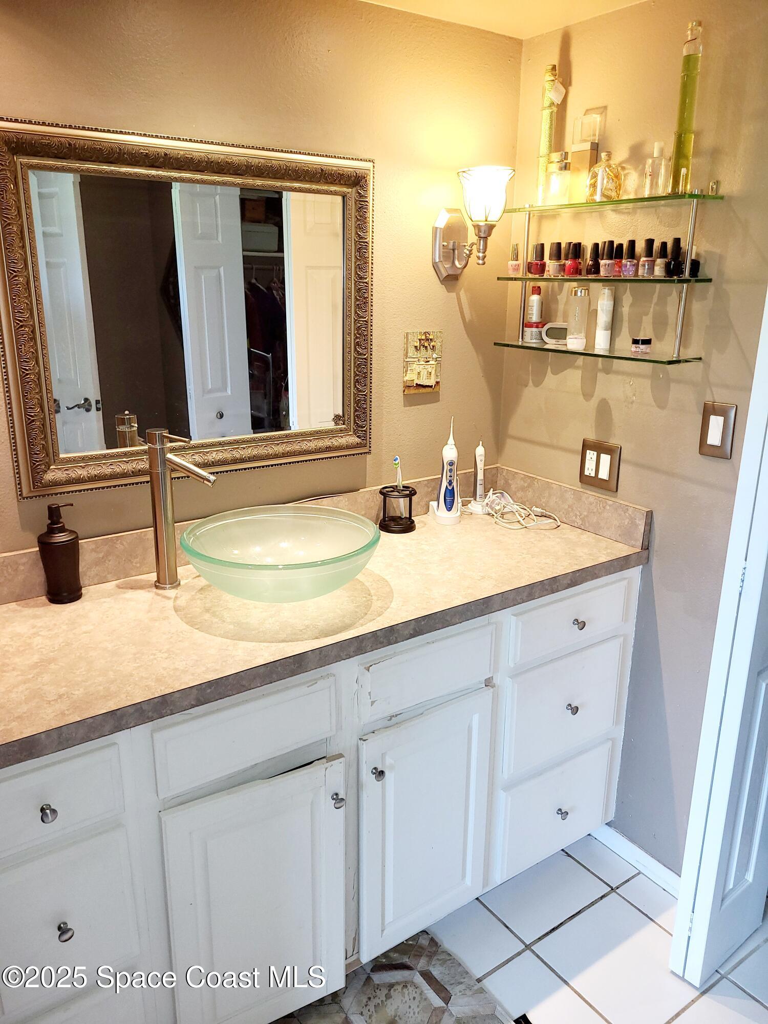145 Augusta Way Melbourne, FL 32940 - Photo 23 of 28 a bathroom with a sink and a mirror