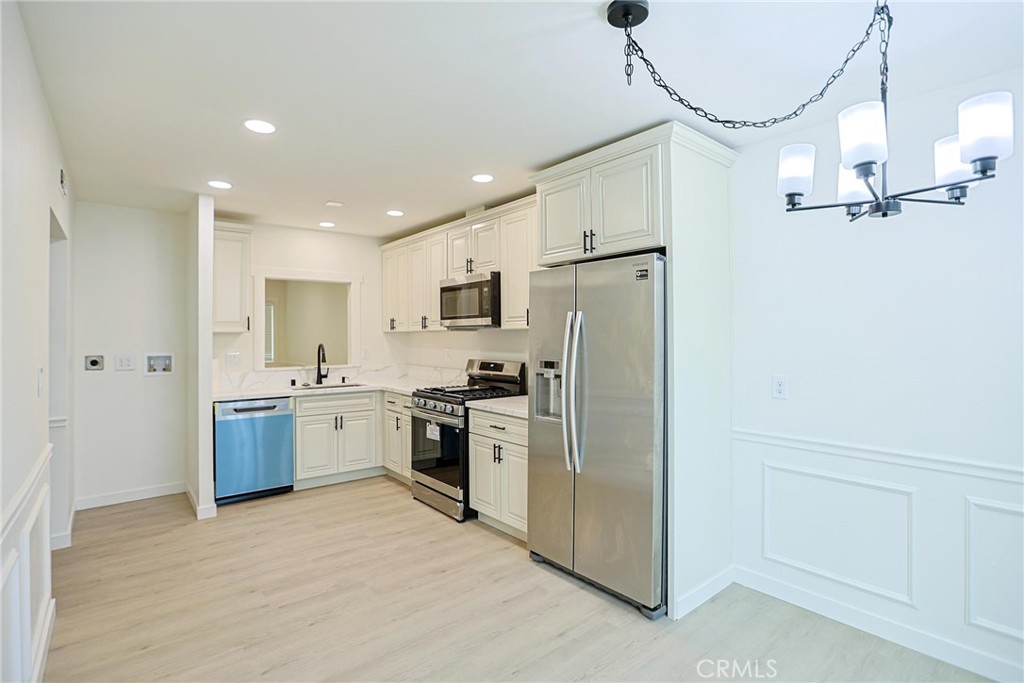 4109 West 5th Street, Unit F2 Santa Ana, CA 92703 - Photo 20 of 41 a kitchen with refrigerator a sink and white cabinets