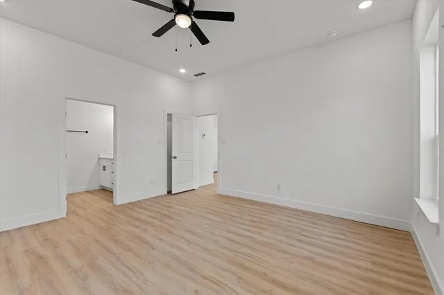 a view of empty room with wooden floor and ceiling fan