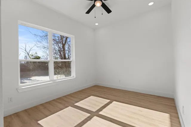 a view of an empty room with a window and wooden floor