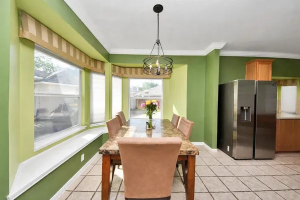 a dining room with granite countertop a refrigerator and a chandelier