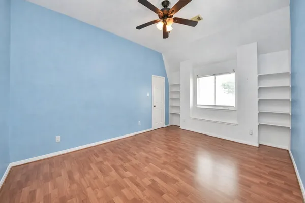 a view of an empty room with a window and wooden floor