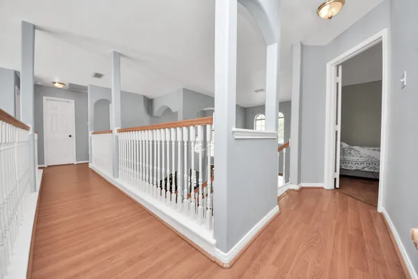 a view of a hallway with wooden floor and a bathroom