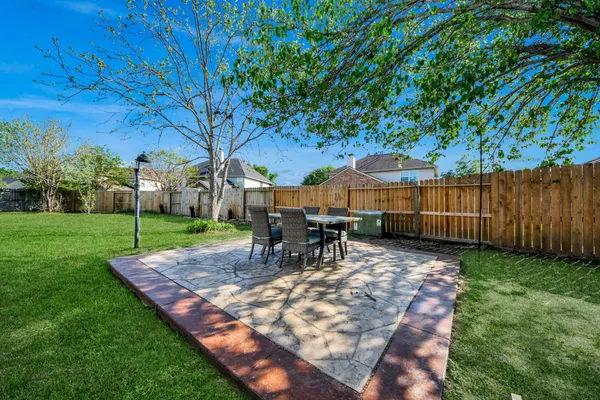 a view of a backyard with table and chairs and a barbeque with wooden fence