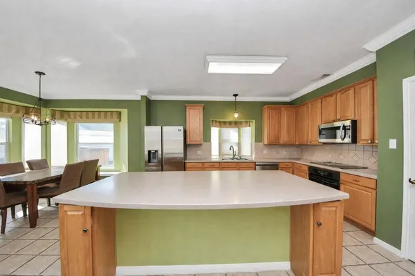 a kitchen with a stove a sink a counter top space and living room view