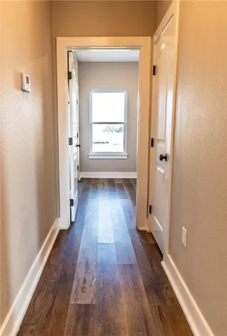 a view of a hallway with wooden floor and a bathroom