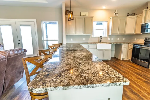 a large kitchen with kitchen island granite countertop a sink and white cabinets