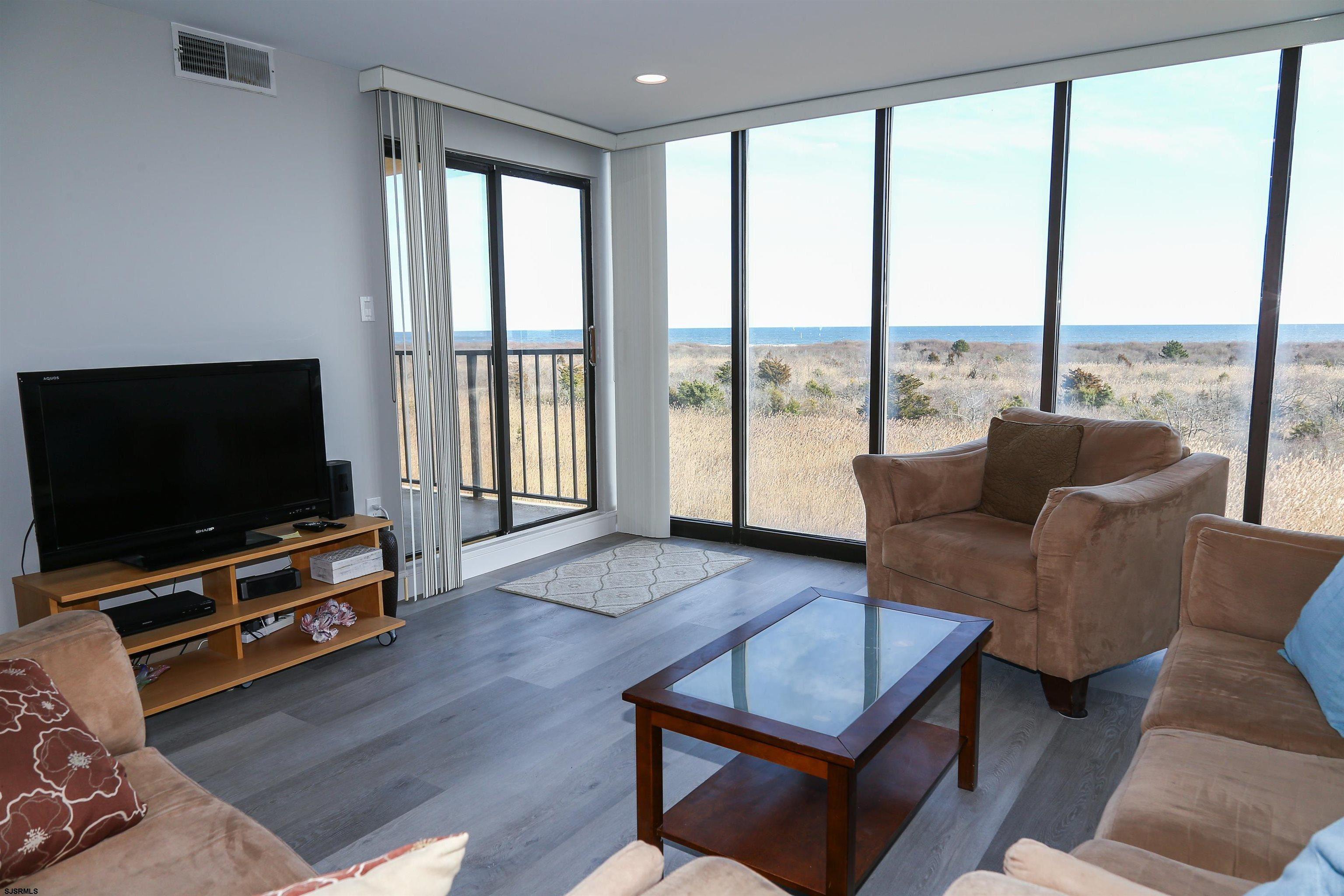 4540 West Brigantine Avenue, Unit N408 Brigantine, NJ 08203 - Photo 15 of 42 a living room with furniture a flat screen tv and a floor to ceiling window