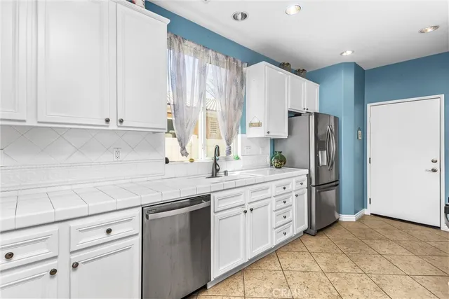 a kitchen with white cabinets and a refrigerator