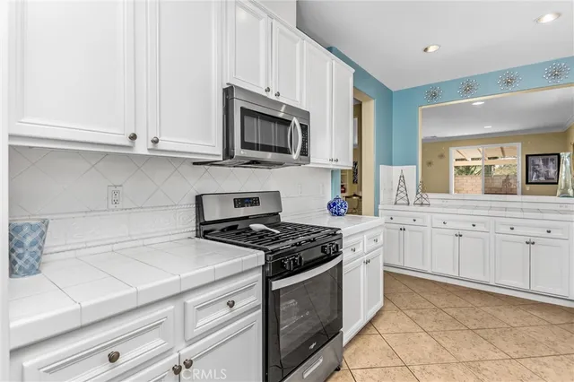 a kitchen with stainless steel appliances granite countertop white cabinets a sink a stove a window and white
