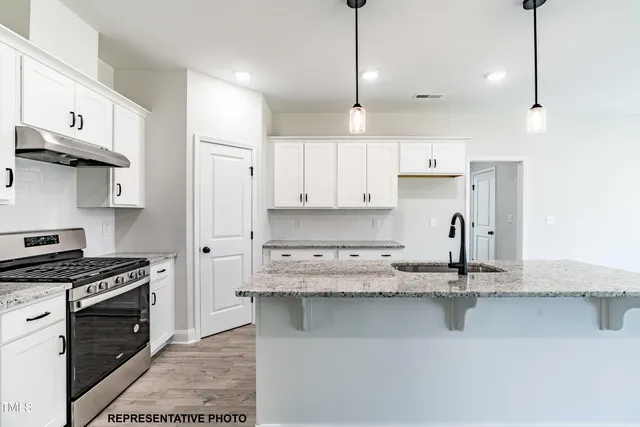 a kitchen with kitchen island granite countertop a sink cabinets and stainless steel appliances