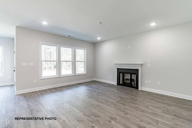 an empty room with wooden floor fireplace and windows