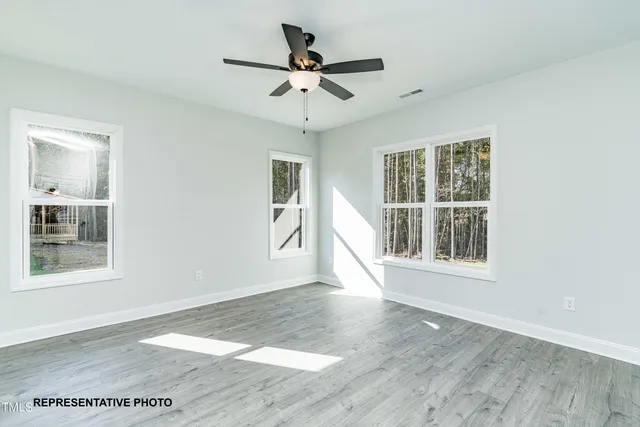 an empty room with wooden floor chandelier and windows