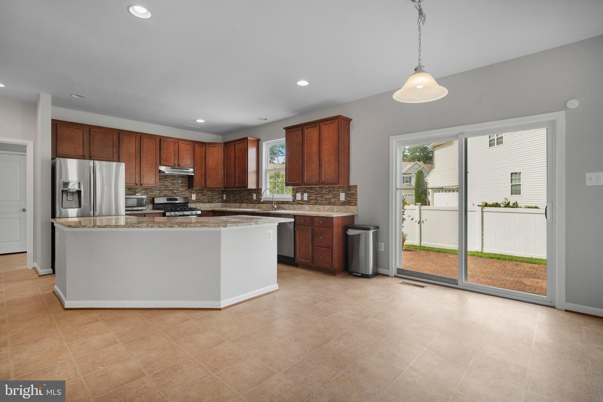 8205 Running Spring Circle Severn, MD 21144 - Photo 23 of 77 a kitchen with stainless steel appliances granite countertop a refrigerator a oven a sink with island and chairs