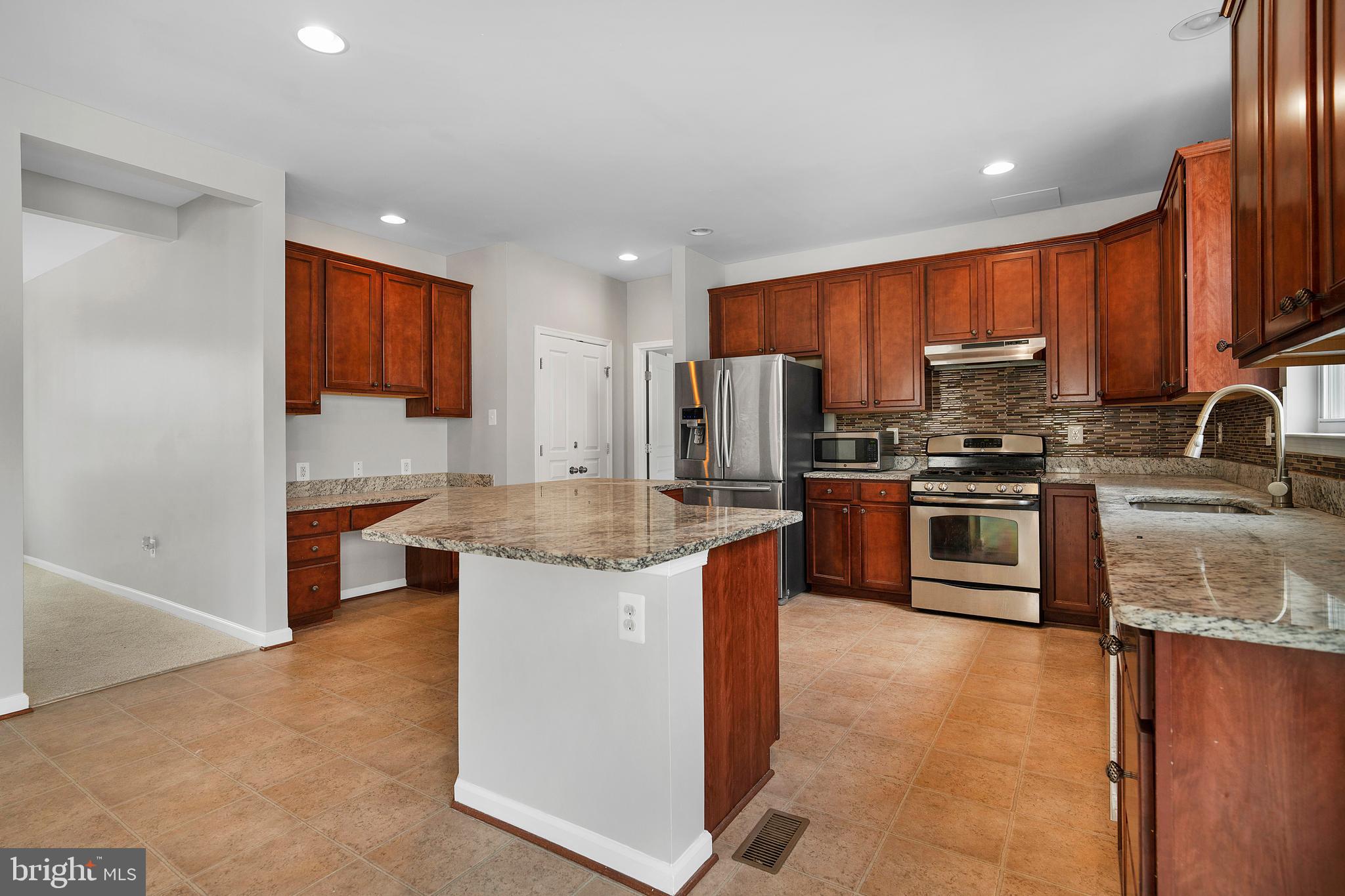 8205 Running Spring Circle Severn, MD 21144 - Photo 25 of 77 a kitchen with stainless steel appliances granite countertop a stove a sink dishwasher a refrigerator and a microwave