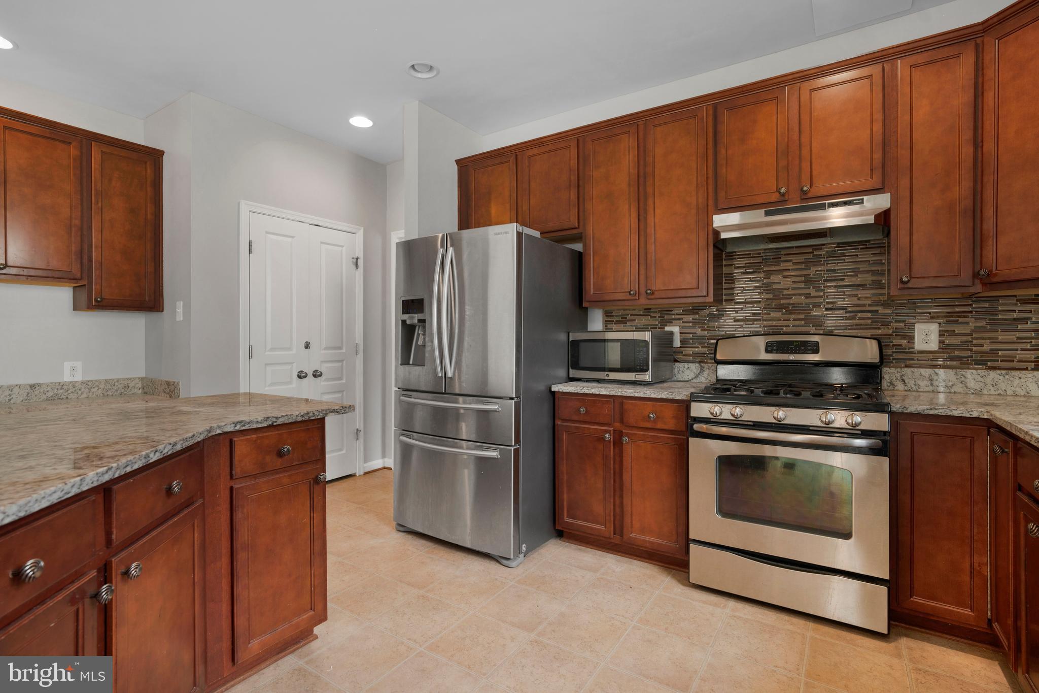 8205 Running Spring Circle Severn, MD 21144 - Photo 30 of 77 a kitchen with stainless steel appliances granite countertop a refrigerator stove and sink