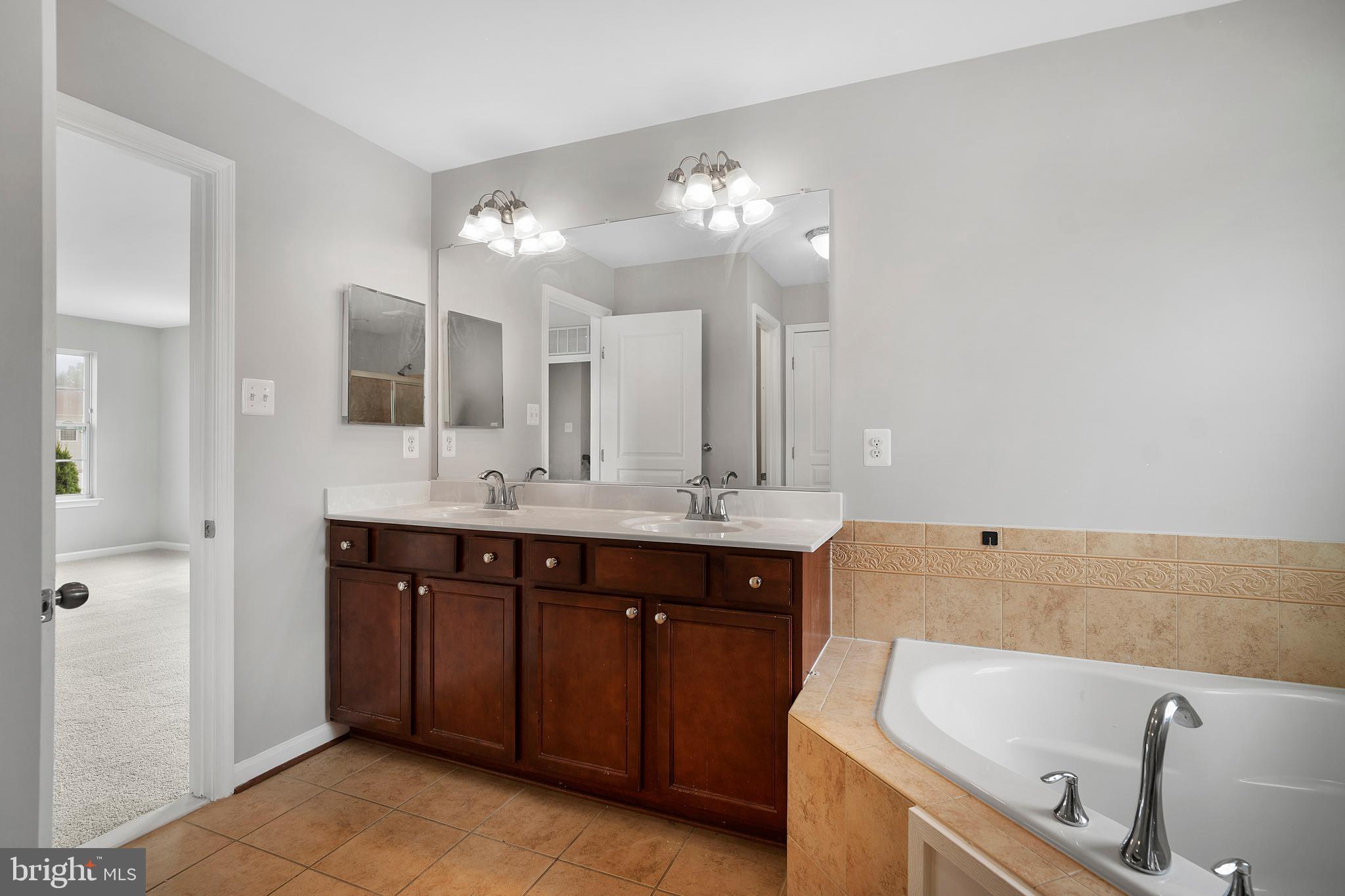8205 Running Spring Circle Severn, MD 21144 - Photo 52 of 77 a spacious bathroom with a tub sink and mirror