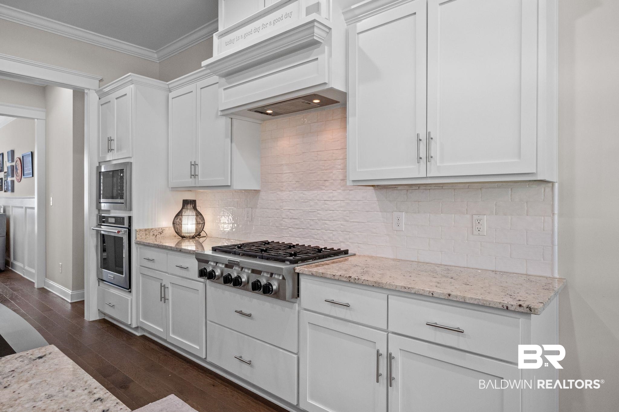 32194 Badger Court Daphne, AL 36527 - Photo 17 of 49 Kitchen with crown molding, white cabinets, stainless steel appliances, dark wood finished floors, and light stone counters
