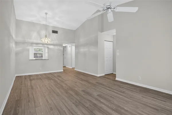 a view of an empty room with wooden floor and a ceiling fan