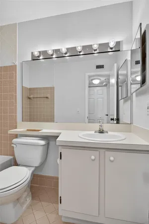 a bathroom with a granite countertop toilet sink and mirror