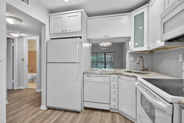 a kitchen with cabinets appliances wooden floor and a window