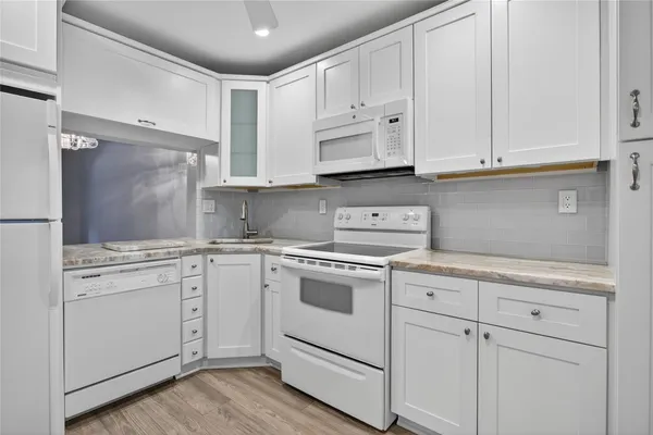 a kitchen with white cabinets and white appliances