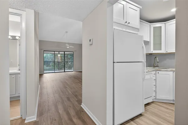 a view of a kitchen with refrigerator and wooden floor