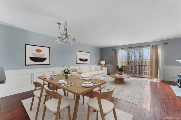 a dining room with wooden floor a chandelier a glass table and chairs