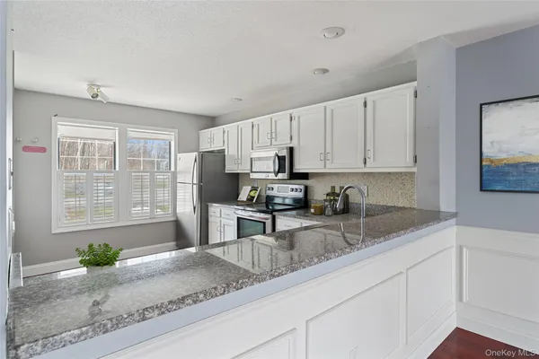 a kitchen with granite countertop a sink a stove and cabinets