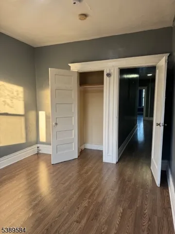 an empty room with wooden floor closet and windows