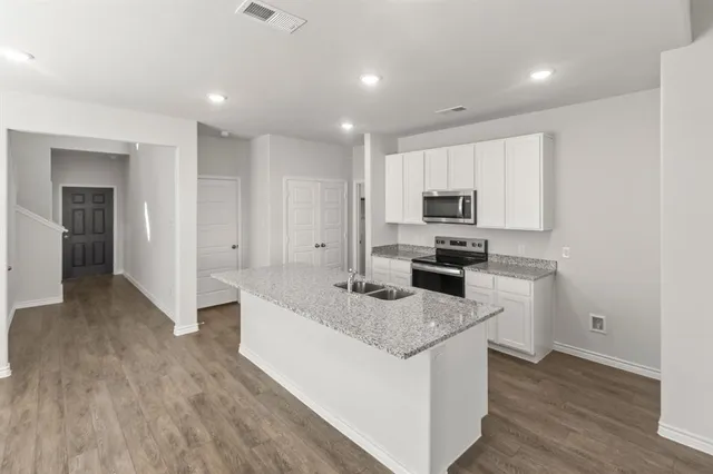a kitchen with granite countertop a sink stove and refrigerator