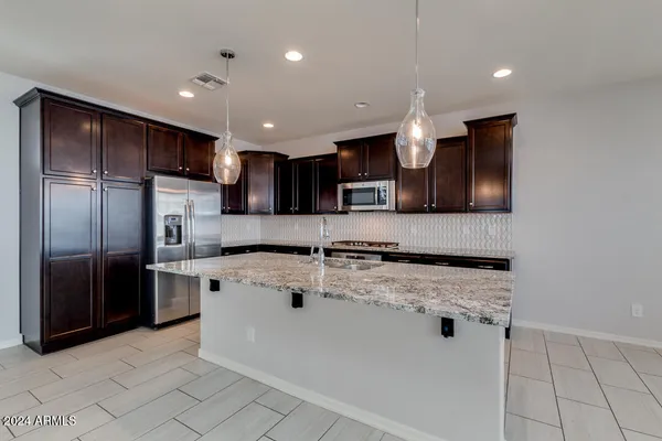 a kitchen with stainless steel appliances kitchen island granite countertop a refrigerator and a sink