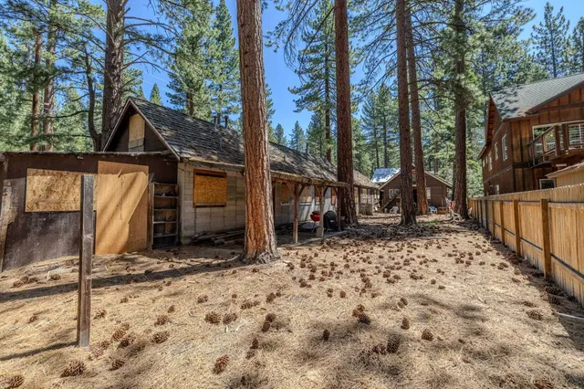 a view of house with wooden fence and large trees