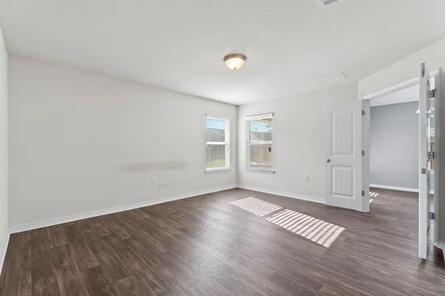 an empty room with wooden floor & windows