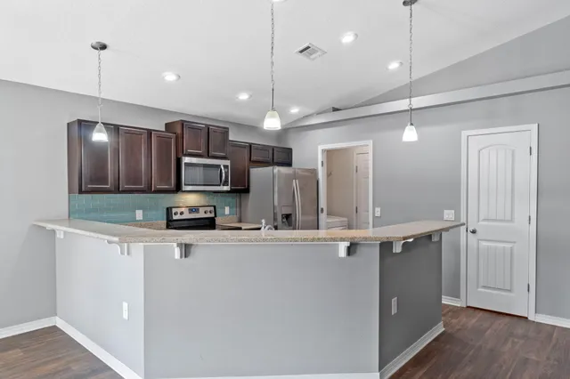 a kitchen with kitchen island a sink stainless steel appliances and wooden floor