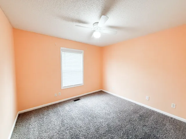 an empty room with a ceiling fan and window
