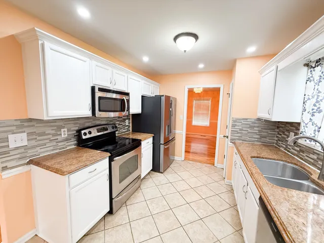 a kitchen with granite countertop a sink a counter top space appliances and cabinets