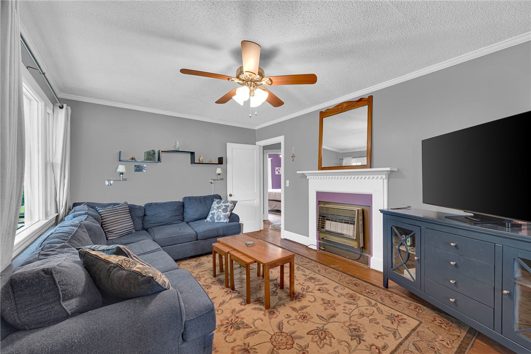 102 Graham Honea Path, SC 29654 - Photo 5 of 29 An inviting living area featuring a ceiling fan, a prominent fireplace, and rich hardwood floors.