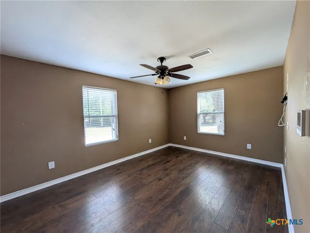 a view of an empty room with a window and wooden floor