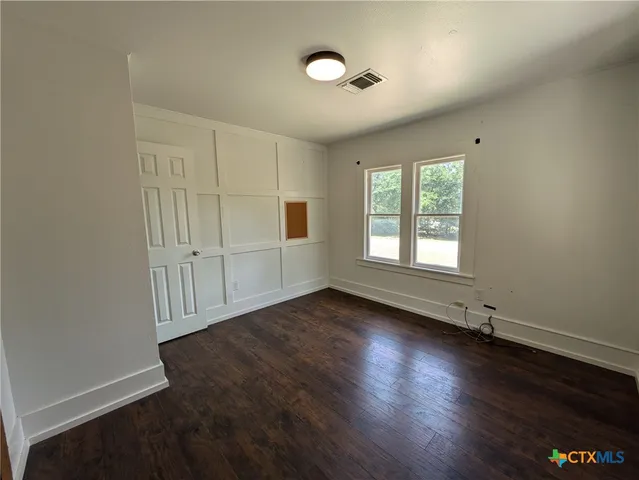 an empty room with wooden floor closet and windows