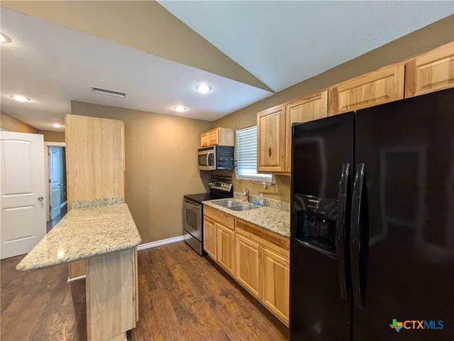 a kitchen with stainless steel appliances granite countertop a refrigerator a stove and a sink