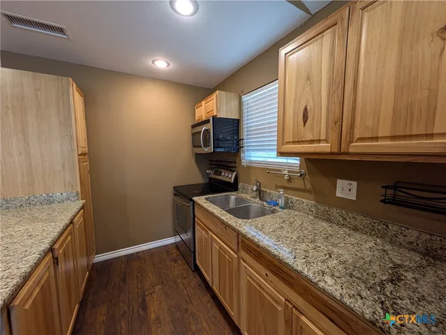 a kitchen with stainless steel appliances granite countertop a sink stove and cabinets